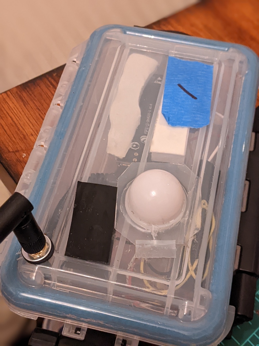 Top of enclosure with new rubber washer installed on antenna, and transparent waterproof tape installed over the light sensor.